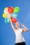 Woman holding balloons against blue sky