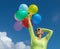 Woman holding balloons against cloud