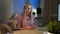 Woman holding bitcoins and thinking. Beautiful blond female sitting in dark room at desk with computer and lamp at night