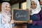 Woman holding a blackboard with open written on it