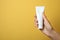 Woman holding blank toothpaste tube on color background