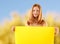 Woman holding blank yellow banner over nature