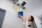 Woman Holding A Blue Bucket Under The Leak Ceiling