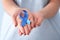 Woman holding blue ribbon, closeup. Colon cancer awareness concept