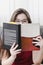 Woman holding a book in front of her with just the eyes out of t