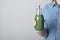 Woman holding bottle with spirulina smoothie on grey background, closeup