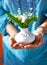 Woman holding bouquet of flower in vase. Blue clothing background