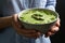 Woman holding bowl with delicious asparagus soup on background, closeup