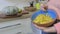 Woman holding bowl and mixing small pieces of pumpkin