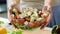 Woman holding bowl of vegetable salad with feta