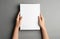 Woman holding brochure with blank cover on grey background, top view.