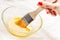 Woman holding brush dipped into whisked egg