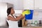 Woman Holding Bucket While Water Droplets Leak From Ceiling