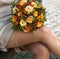 Woman holding a bunch of orange roses in her hands wearing hold-up stockings.