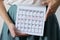 Woman holding calender with marked missed period. Unwanted pregnancy, woman`s health and delay in menstruation.