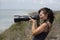 Woman holding a camera with a long zoom lens on coast in South Africa.