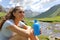 Woman holding canteen contemplating a mountain river