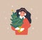 Woman holding Christmas tree in pot. Smiling girl preparing for winter holidays. People buying Christmas fir on the fair