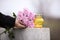 Woman holding chrysanthemum flowers near grey granite tombstone with candle outdoors, closeup. Funeral ceremony