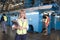 Woman Holding Clipboard With Operators Behind At Factory