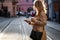 Woman holding coffee cup and smart phone and crossing street in rush