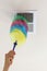 A woman holding colorful, non scratch plush microfiber duster brush is removing the dust from the air duct