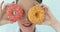 Woman holding colorful pink donuts against her eyes