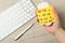 Woman holding computer mouse with sticky note at wooden table, top view. April fool`s day