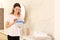 Woman holding container with laundry detergent capsules in bathroom