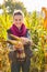 Woman holding corn while standing in cornfield