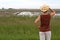 Woman holding cowboy hat looking at a farm field full of water.