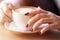 Woman holding cup of capuccino on wooden table.