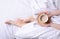 Woman holding cup of coffee in the white linens bed