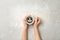 Woman holding cup of delicious hot coffee with foam and smile on light background, top view. Happy morning, good mood