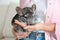 Woman holding cute chinchilla in room