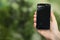 Woman holding damaged smartphone on blurred green background, closeup with space for text. Device repairing