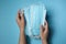 Woman holding disposable face masks on blue background, closeup. Protective measures during coronavirus quarantine