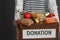 Woman holding donation box with food on gray, closeup