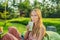 Woman holding and drinks Matcha green tea latte in an outdoor cafe