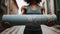 Woman holding dusty green yoga mat in the street