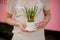 Woman holding a flower pot in the shape of cup of tea with the muscari with green leaves