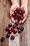 Woman is holding fresh cherries in hands on wood table