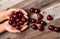 Woman is holding fresh cherries in hands on wood table