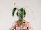 Woman holding in front of her face flower vase with dead plants