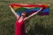Woman holding the Gay Rainbow Flag on a green meadow outdoors. Happiness, freedom and love concept for same sex couples. LIfestyle