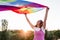Woman holding the Gay Rainbow Flag at sunset. Happiness, freedom and love concept for same sex couples. LIfestyle outdoors