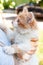 woman holding  ginger cat outdoor illuminated with sunlight