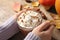 Woman holding glass cup of tasty pumpkin spice latte at wooden table