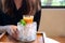 Woman holding a glass of mixed orange and carrot juice in a jar of ice with mint leaves in cafe