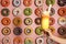 Woman holding glass of tasty milk shake with sweets near decorated wall, closeup.